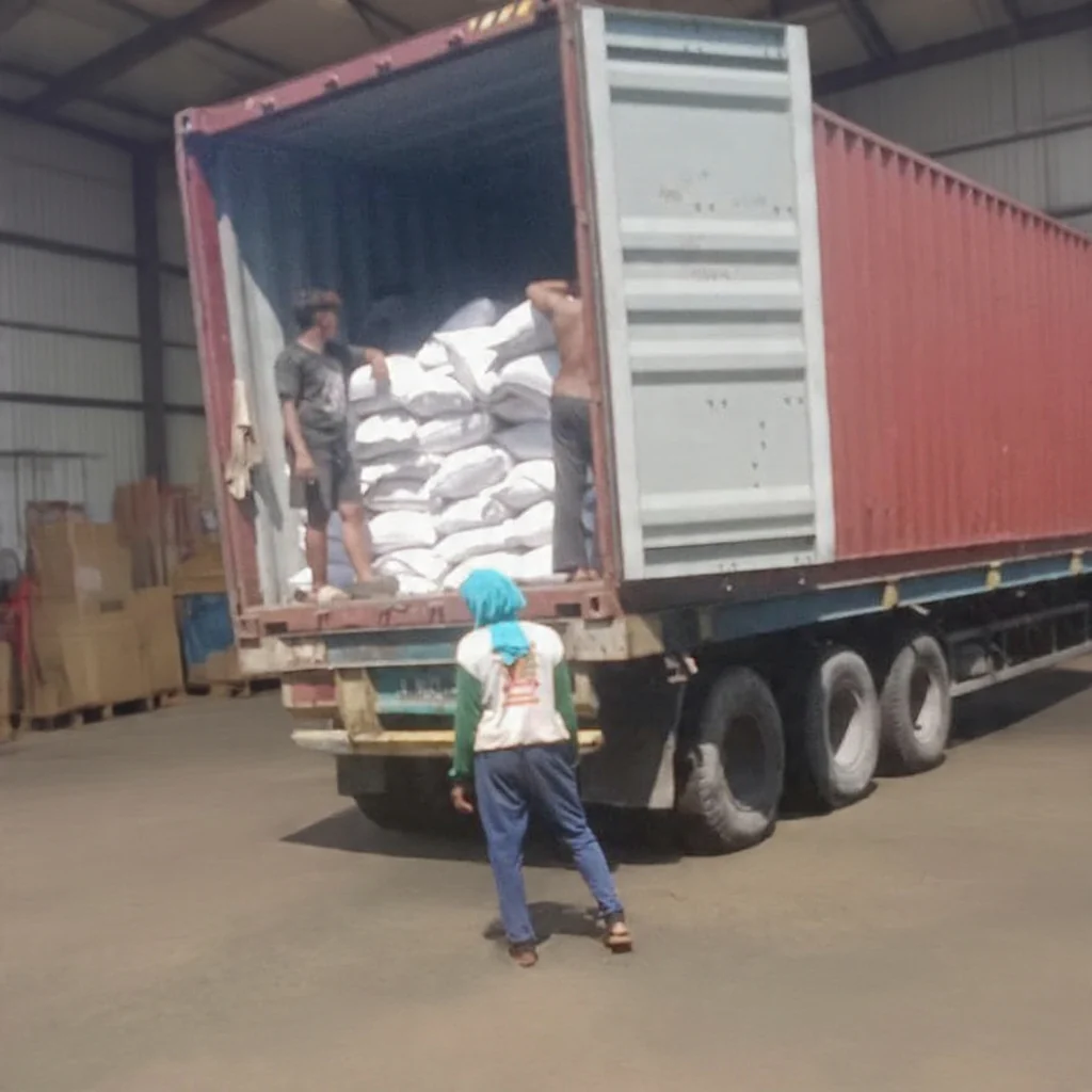 Workers loading bagged material into an export container